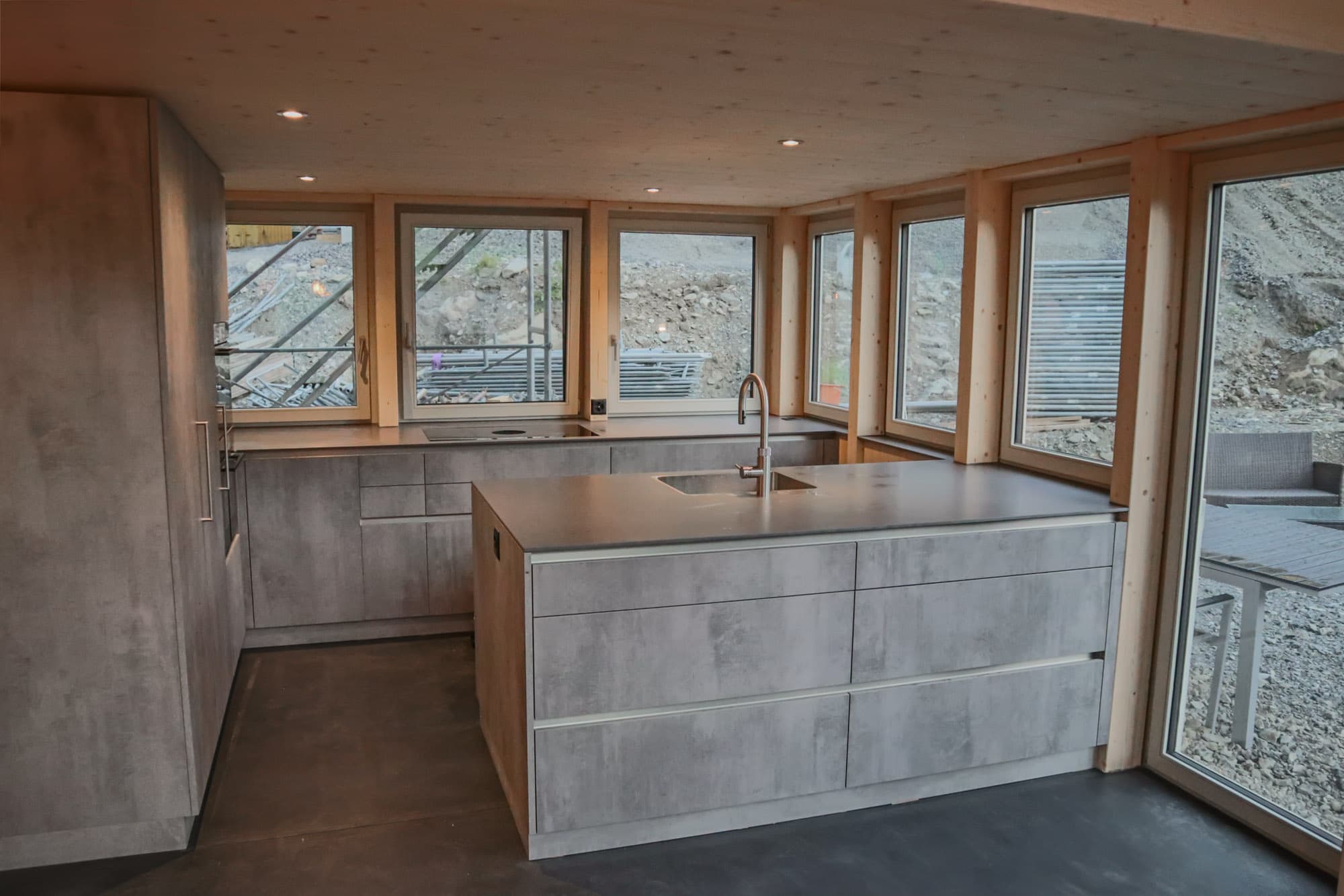 Küche in Betonoptik mit grossen Holzfenstern